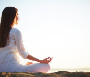 woman-sitting-in-yoga-pose-on-the-beach